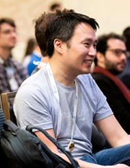 Man sitting in seat smiling with other people sitting in an audience