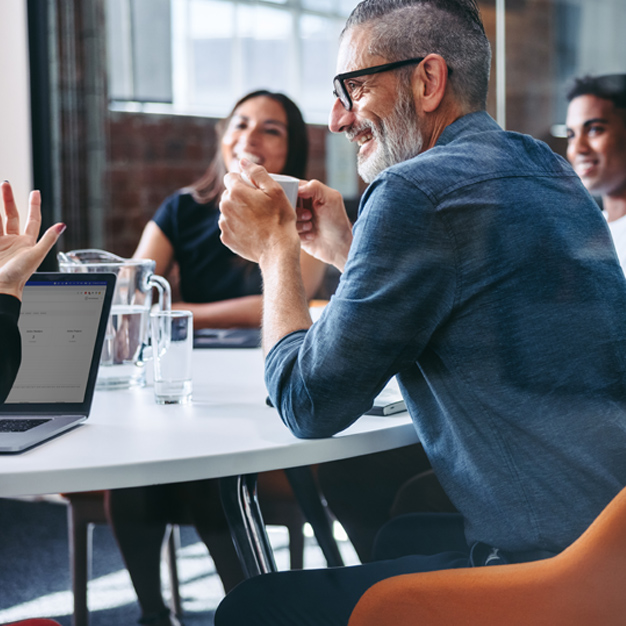 People smiling in a meeting in modern conference room with older gentleman